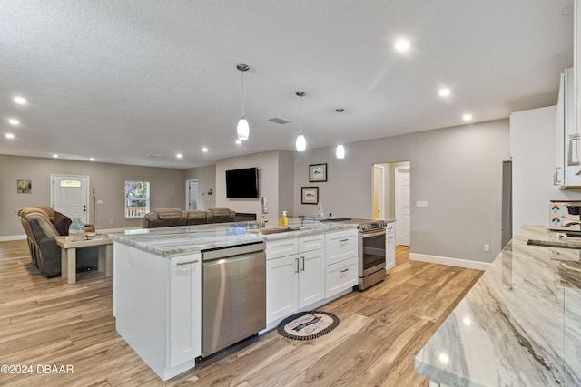 kitchen featuring light hardwood / wood-style floors, appliances with stainless steel finishes, light stone countertops, white cabinets, and pendant lighting