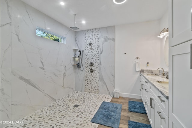 bathroom featuring wood-type flooring, vanity, and a tile shower