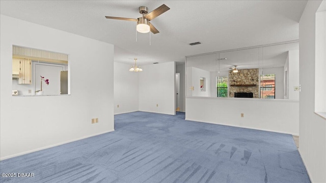 unfurnished living room with a stone fireplace, a textured ceiling, ceiling fan, and carpet flooring