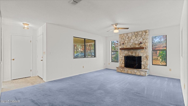 unfurnished living room featuring ceiling fan, light colored carpet, a fireplace, and a textured ceiling