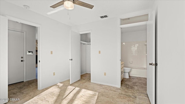 unfurnished bedroom featuring ceiling fan, ensuite bathroom, a spacious closet, and a closet