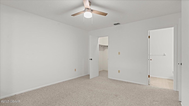 unfurnished bedroom featuring a spacious closet, light carpet, ceiling fan, and a closet