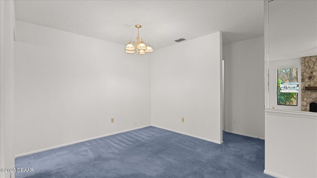 unfurnished room featuring a chandelier, a textured ceiling, and dark carpet