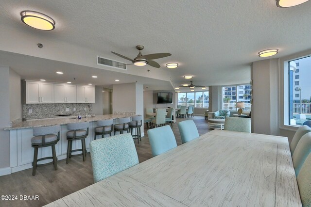 dining room with ceiling fan, sink, dark wood-type flooring, and a textured ceiling