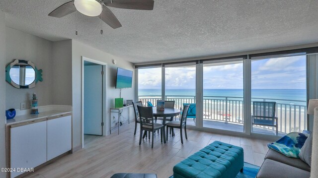 dining area with floor to ceiling windows, ceiling fan, a textured ceiling, and light wood-type flooring