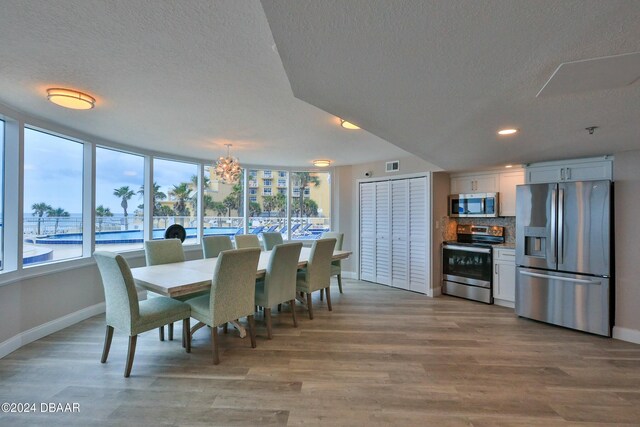 dining room featuring a notable chandelier, a textured ceiling, and light hardwood / wood-style flooring