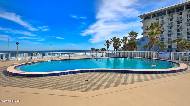 view of pool featuring a water view and a patio