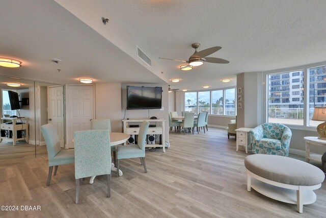 dining space featuring ceiling fan, a textured ceiling, and light hardwood / wood-style flooring