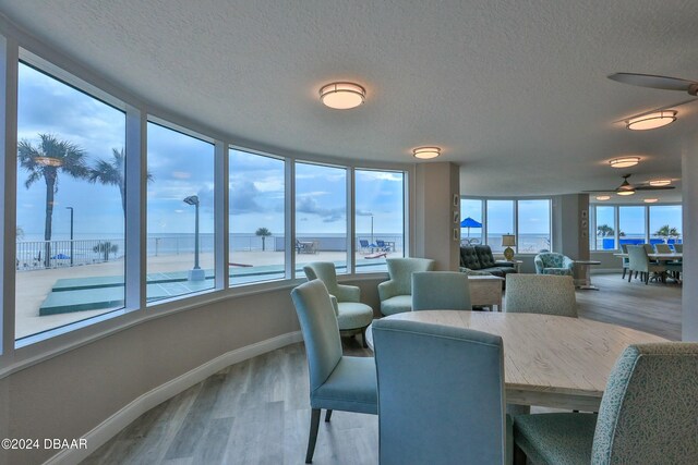 dining area with plenty of natural light, a water view, a textured ceiling, and hardwood / wood-style flooring