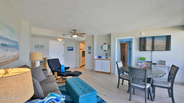 living room with ceiling fan, light hardwood / wood-style floors, and a textured ceiling