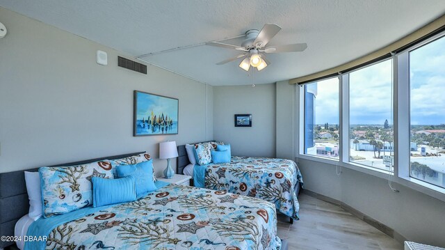 bedroom featuring ceiling fan, light hardwood / wood-style floors, and a textured ceiling