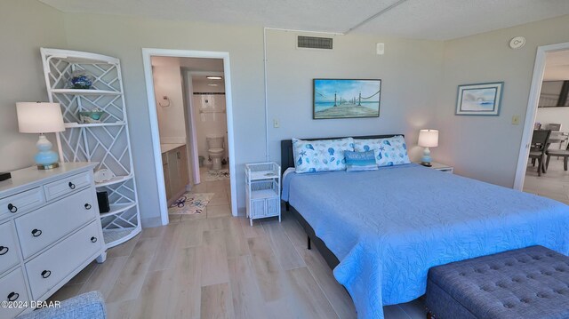 bedroom with light wood-type flooring and connected bathroom