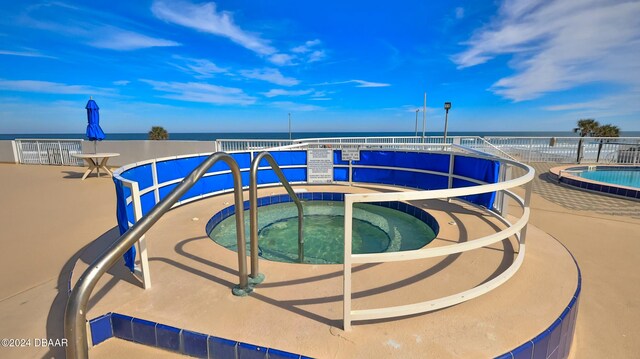 view of pool with a community hot tub and a water view