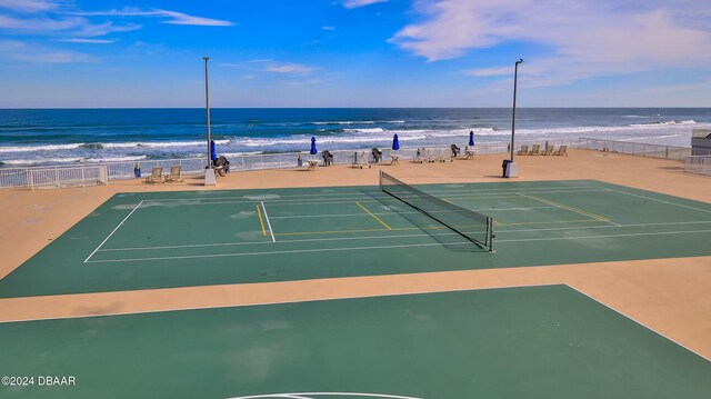 view of sport court featuring a water view and a beach view