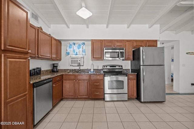 14 Essex Dr, Ormond Beach, FL 32176 - kitchen with stainless steel appliances, beam ceiling, dark stone countertops, light tile patterned flooring, and brown cabinets