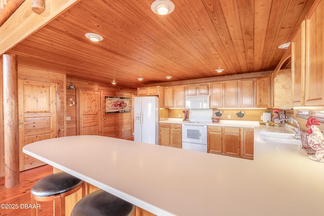 109 Avalon Dr, Ormond Beach, FL 32176 - kitchen featuring a breakfast bar, light countertops, a sink, white appliances, and a peninsula