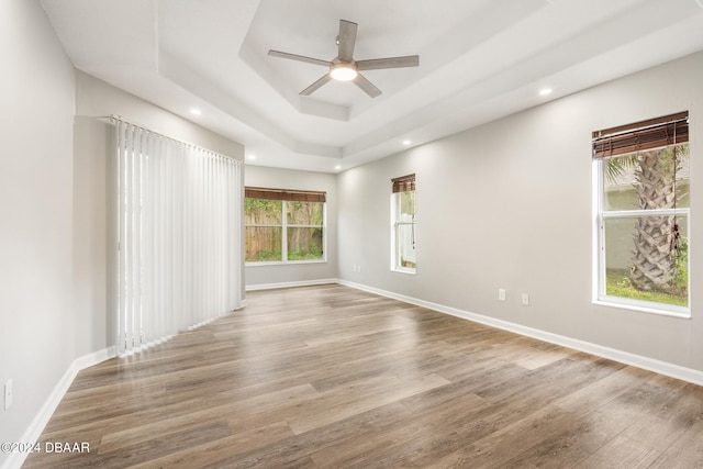 unfurnished room featuring hardwood / wood-style floors, ceiling fan, and a tray ceiling