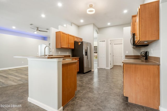 kitchen featuring stainless steel appliances, dark tile patterned floors, sink, kitchen peninsula, and ceiling fan