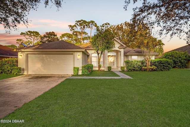 ranch-style house featuring a garage and a yard