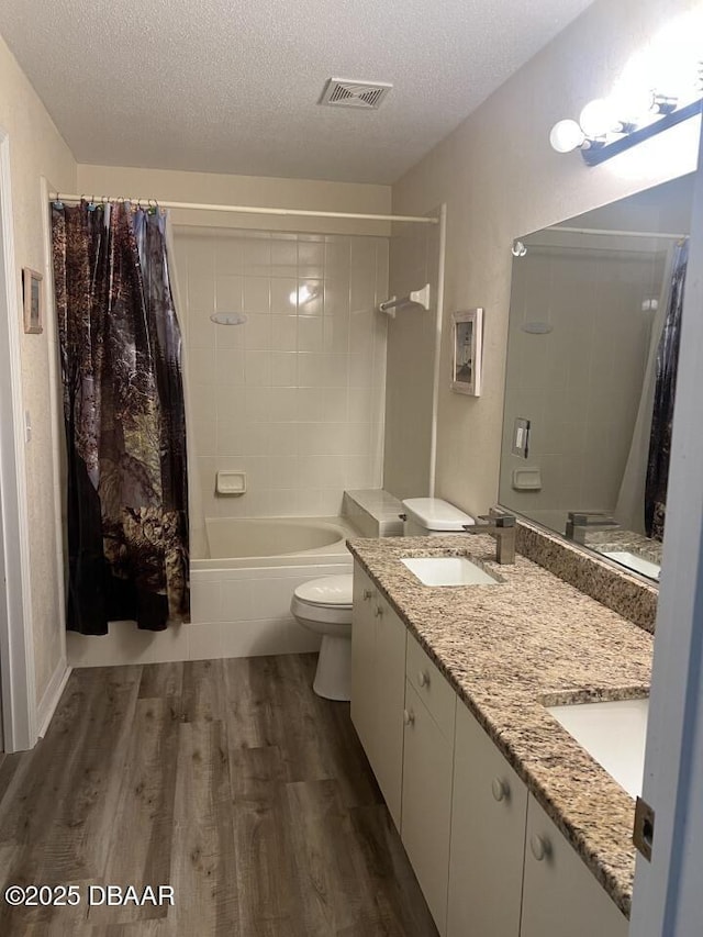 539 Lake Bridge Dr, Ormond Beach, FL 32174 - bathroom featuring a textured ceiling, wood finished floors, toilet, shower / bathtub combination with curtain, and double vanity