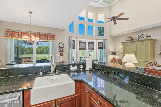 kitchen with french doors, a towering ceiling, sink, decorative light fixtures, and dark stone countertops