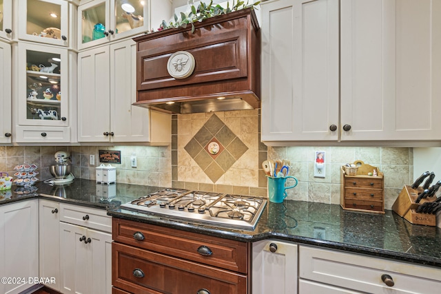 kitchen with dark stone counters, white cabinetry, backsplash, and stainless steel gas stovetop