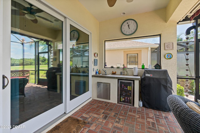 sunroom featuring ceiling fan, beverage cooler, and wet bar