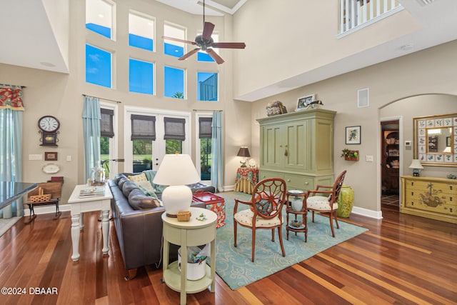 living room featuring dark wood-type flooring, a towering ceiling, ceiling fan, and french doors