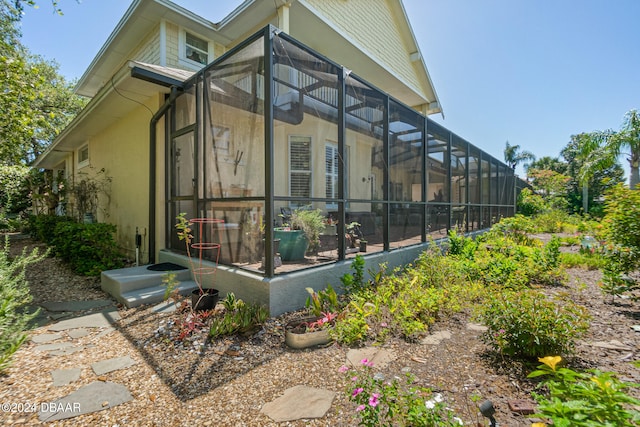 view of property exterior with glass enclosure and a sunroom