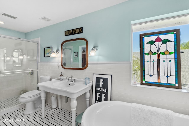 bathroom featuring toilet, tile walls, tile patterned flooring, and separate shower and tub