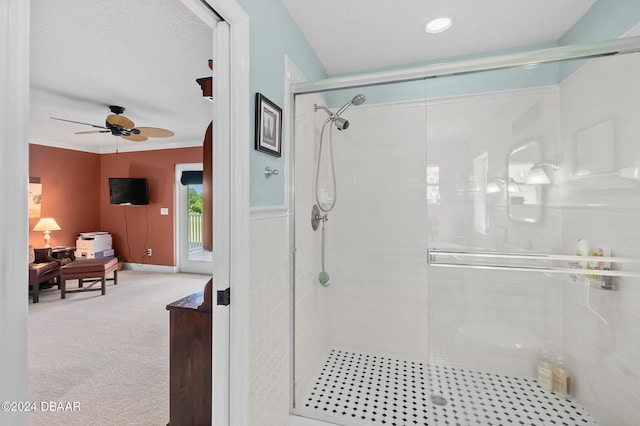 bathroom featuring ceiling fan, ornamental molding, and a shower with shower door