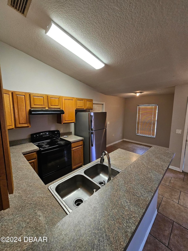 kitchen with a textured ceiling, stainless steel refrigerator, dark tile patterned flooring, black / electric stove, and vaulted ceiling