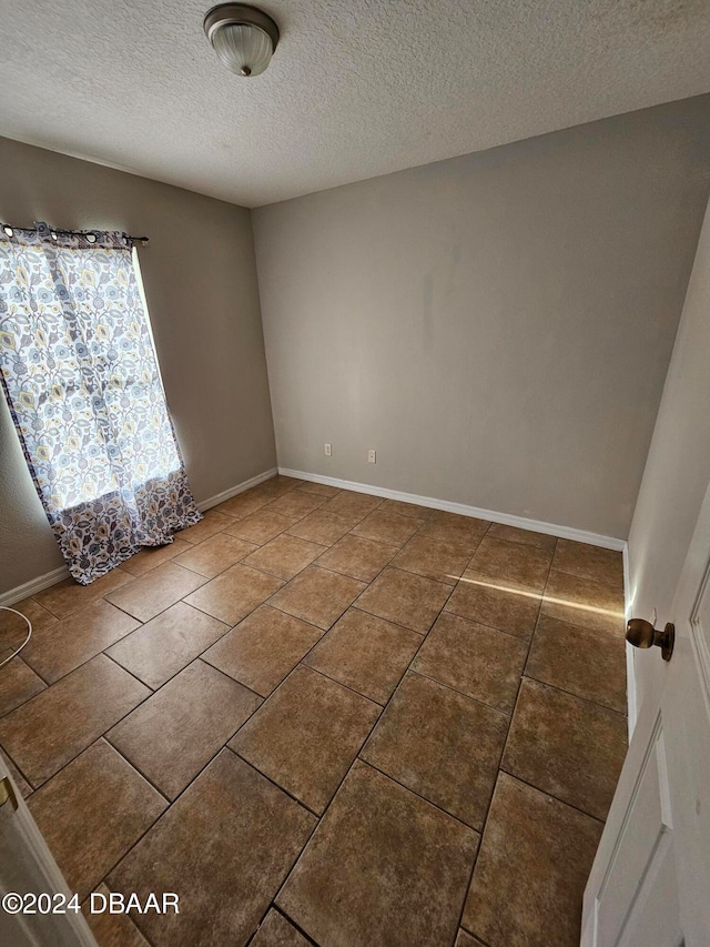 spare room featuring a textured ceiling and tile patterned floors