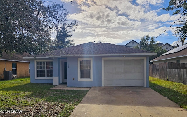 ranch-style home with central AC unit, a garage, and a front yard