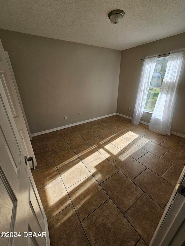 spare room featuring tile patterned flooring and a textured ceiling