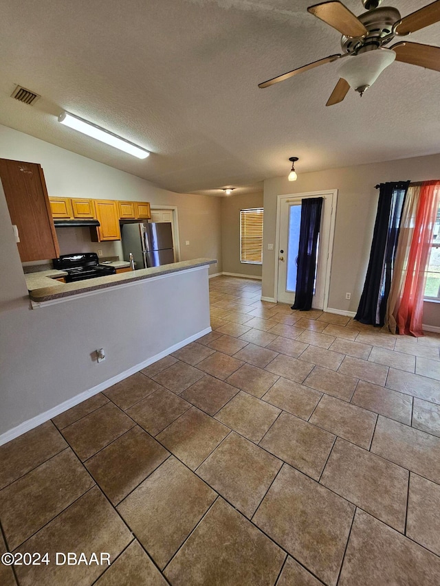 kitchen with ceiling fan, a textured ceiling, black gas range, stainless steel fridge, and vaulted ceiling