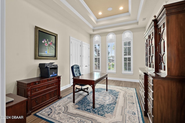 home office with hardwood / wood-style floors, a raised ceiling, and crown molding