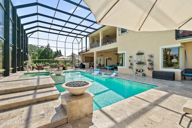 view of swimming pool with glass enclosure, a patio, ceiling fan, and an in ground hot tub