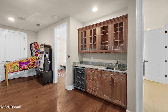 kitchen featuring beverage cooler, sink, light stone counters, and dark hardwood / wood-style flooring