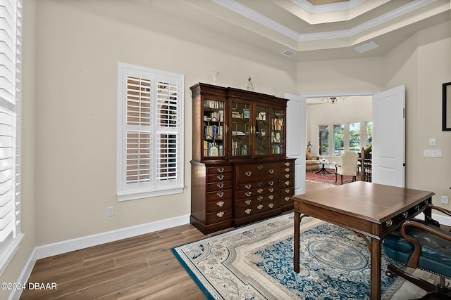 office space with wood-type flooring, a tray ceiling, an inviting chandelier, and ornamental molding