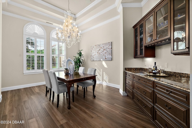 dining space featuring dark wood-type flooring, a chandelier, crown molding, and a tray ceiling