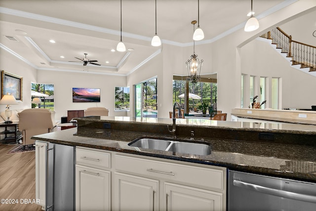 kitchen featuring sink, stainless steel dishwasher, white cabinetry, decorative light fixtures, and dark stone countertops