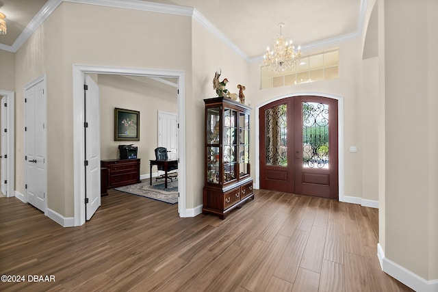 entrance foyer featuring hardwood / wood-style flooring, a chandelier, a high ceiling, and ornamental molding