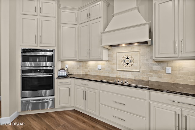 kitchen featuring dark wood-type flooring, stainless steel double oven, custom exhaust hood, and white cabinets