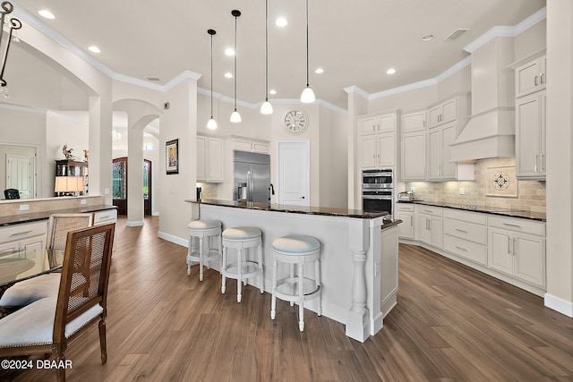 kitchen with crown molding, white cabinetry, appliances with stainless steel finishes, hanging light fixtures, and dark wood-type flooring