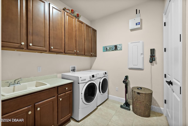 laundry area featuring electric panel, light tile patterned floors, cabinets, sink, and washing machine and clothes dryer