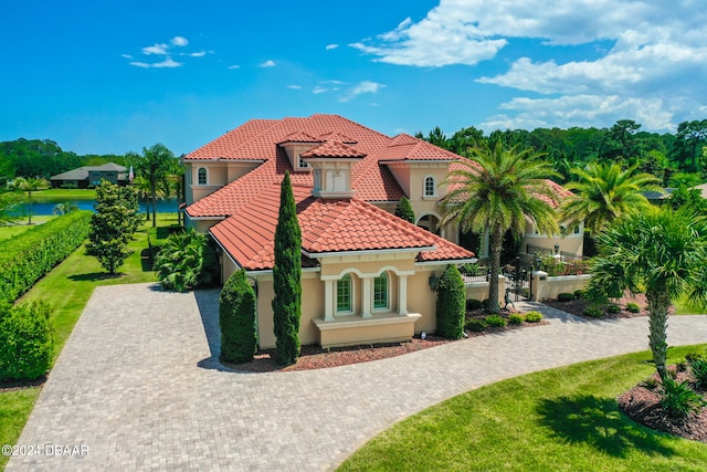 mediterranean / spanish-style house with a front yard and a water view