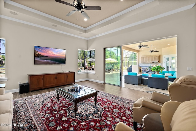 living room with ornamental molding, a tray ceiling, and light hardwood / wood-style floors