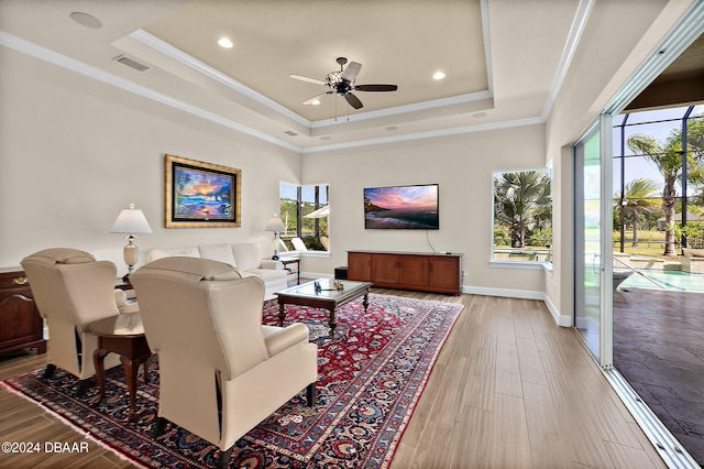 living room featuring hardwood / wood-style flooring, a healthy amount of sunlight, ceiling fan, and a tray ceiling