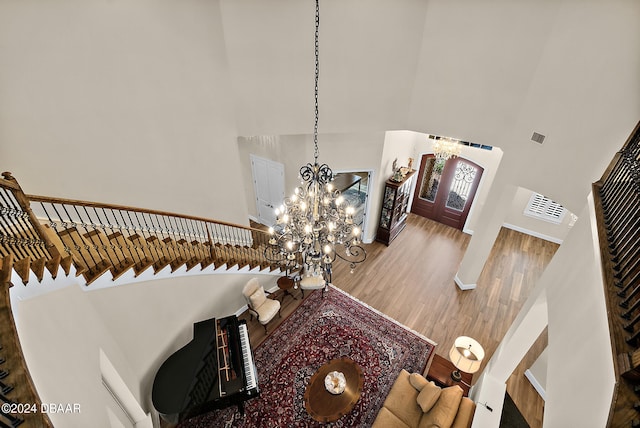 interior space with a towering ceiling, wood-type flooring, and a notable chandelier